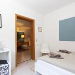 Schlafzimmer mit Bett, Stuhl und Schrank. Durchgang in Wohnbereich mit Lampen.