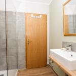 Badezimmer mit Dusche, Waschbecken und Spiegel.