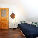 Schlafzimmer mit Dachschräge, Bett, Nachttisch und Holztür.