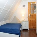 Schlafzimmer mit Bett, Nachttisch und Holztür