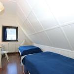 Zimmer mit zwei Betten, Schreibtisch und Fenster. Dachschrägen Decke und Holzboden.