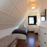 Schlafzimmer mit Dachschrägen, Bett, Schrank und Fenster.