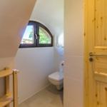 Bad mit Toilette und Holztür. Bogenfenster mit Blick nach draußen.