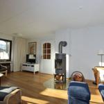 Wohnzimmer mit Holzofen, Fernseher und Sitzgelegenheiten.