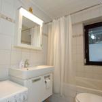 Badezimmer mit Waschbecken, Spiegel, Dusche, Badewanne und Fenster.