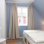 Schlafzimmer mit Bett, Fenster, Vorhängen und Lampen.