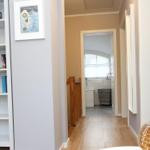 Flur mit Bücherregal, Treppe und Blick in die Küche.