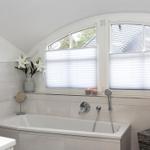 Bad mit Badewanne, Fenster mit Jalousien und Blumen