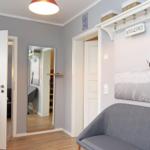 Eingangsbereich mit grauer Couch, Wandbild und Kleiderhaken. Durchgänge zu weiteren Räumen.