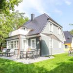 Ein zweistöckiges Haus mit Terrasse und Garten. Fahrräder stehen bereit.