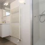 Badezimmer mit Dusche, Waschbecken und Heizkörper