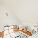 Schlafzimmer mit Dachschrägen, Bett, Nachttisch und Stauraumkiste.