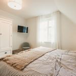 Schlafzimmer mit Bett, Kleiderschrank, Fenster und Fernseher an der Wand.