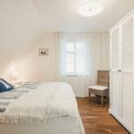 Schlafzimmer mit Bett, Kleiderschrank und Fenster mit Vorhängen.