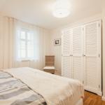 Schlafzimmer mit Bett, Kleiderschrank und Fenster mit Vorhängen.
