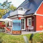 Rotes Haus mit Balkon, Terrasse und Strandkorb im Garten.