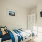 Schlafzimmer mit Bett, Kleiderschrank und Wandbild. TV an der Wand.