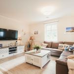 Wohnzimmer mit Sofa, Couchtisch und Fernseher an der Wand.