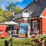 Rotes Haus mit Balkon, Gartenbereich und Strandkorb.