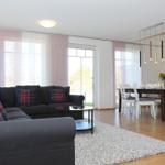 Wohn- und Essbereich mit Sofa, Tisch und Stühlen. Holzboden und große Fenster.