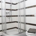Badezimmer mit Dusche, Toilette und Fenster. Wände mit weißen und braunen Streifen.