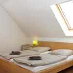 Schlafzimmer mit Doppelbett, Dachfenster und Nachttisch.