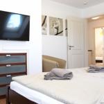 Schlafzimmer mit Bett, Fernseher und Schrank. Türen führen in angrenzende Räume.