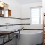 Badezimmer mit Badewanne, Waschbecken und Holzregal
