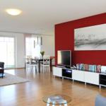 Wohn- und Essbereich mit roter Wand, TV, Sofa und Esstisch.