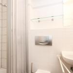 Badezimmer mit Dusche, Waschbecken und Spiegel.