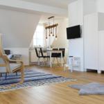 Wohn- und Essbereich mit Holzboden, TV, Schrank und Sitzgelegenheiten.