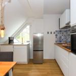 Küche mit Holzoberflächen, Kühlschrank und Ofen. Dachfenster und hängende Lampen.