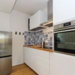 Küche mit weißer Einbauküche, Edelstahl-Kühlschrank und integriertem Backofen.