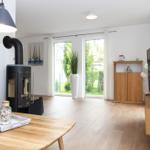 Wohnzimmer mit Holzboden, Kaminofen, TV und Blick auf Garten.