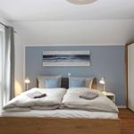 Schlafzimmer mit Doppelbett, Wandbild und zwei Nachttischen mit Lampen.