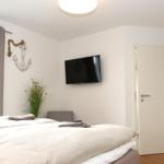 Schlafzimmer mit Bett, Fernseher und Fenster mit Blick auf Grün.