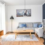 Wohnzimmer mit Sofa, Couchtisch, Fernseher und Kaminofen.