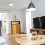 Wohnzimmer mit Holzboden, Fernseher, Kamin und Holzmöbel.