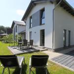 Moderne Villa mit Terrasse, Garten und Liegestühlen. Außenbereich mit Tisch und Stühlen.