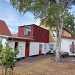 Ein Haus mit rotem und gelbem Anbau, Terrasse mit Tisch, Stühlen und einem Baum.