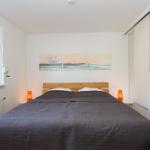 Schlafzimmer mit Bett, Fenster, Schrank und Wandbildern.