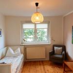 Zimmer mit Bett, Sessel, Fenster und Deckenleuchte.