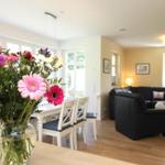 Ein Essbereich mit Blumen und ein Wohnzimmer mit schwarzer Couch.