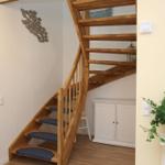 Holztreppe mit blauen Stufen, weiße Schrankwand und Pflanze auf Ständer