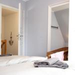 Schlafzimmer mit Bett, Handtuch und Blick in angrenzende Räume.
