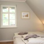 Schlafzimmer mit Dachschräge, Fenster, Bett und Stuhl.
