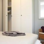 Schlafzimmer mit Bett, Kleiderschrank und Wickerstuhl.