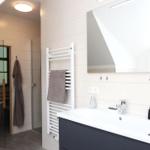 Badezimmer mit Dusche, Toilette und Waschbecken mit Spiegel.