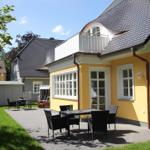 Gelbes Haus mit Balkon, Terrasse und Garten. Tisch und Stühle im Freien.