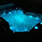 Ein Whirlpool mit blauer Beleuchtung und sprudelndem Wasser in der Dunkelheit.